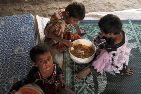Niños paquistaníes se reparten una ración de comida.| Afp