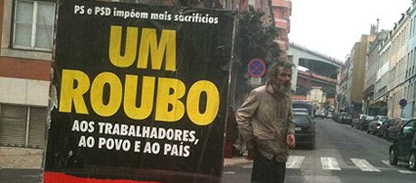 Una persona sin hogar, en una calle de Lisboa, junto a un cartel de la huelga.| A. F.