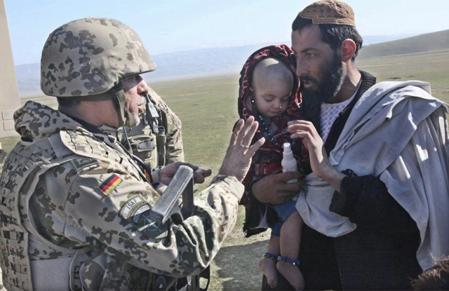 Un soldado de la OTAN reparte medicinas a una familia afgana. | Efe