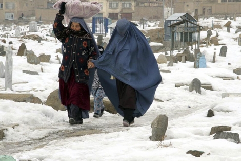Dos mujeres afganas caminan por un cementario nevado en Kabul.| Efe