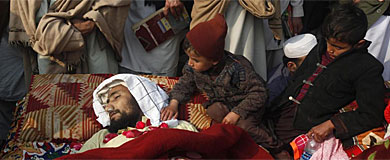Un niño, junto a uno de los 15 cadáveres, en Peshawar.| Reuters