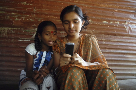 Dos chicas juegan con un móvil en la localidad de Tumni Pada, en Bombay (India). | Efe