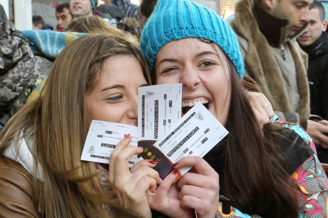 Dos jóvenes muestran su alegría tras conseguir dos entradas de fútbol. | Efe
