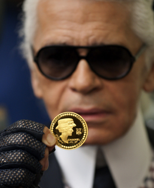 Karl Lagerfeld muestra orgulloso la moneda con la eficie de Coco Chanel. FOTO: REUTERS.